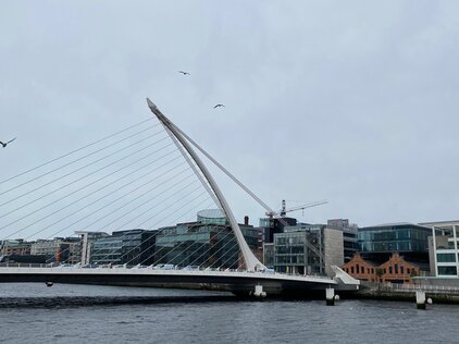 Foto einer langen, weißen Brücke vor einer Stadt. 