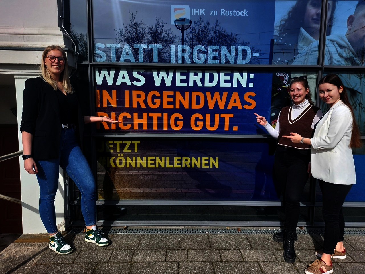 Drei Frauen vor einem Poster der IHK.