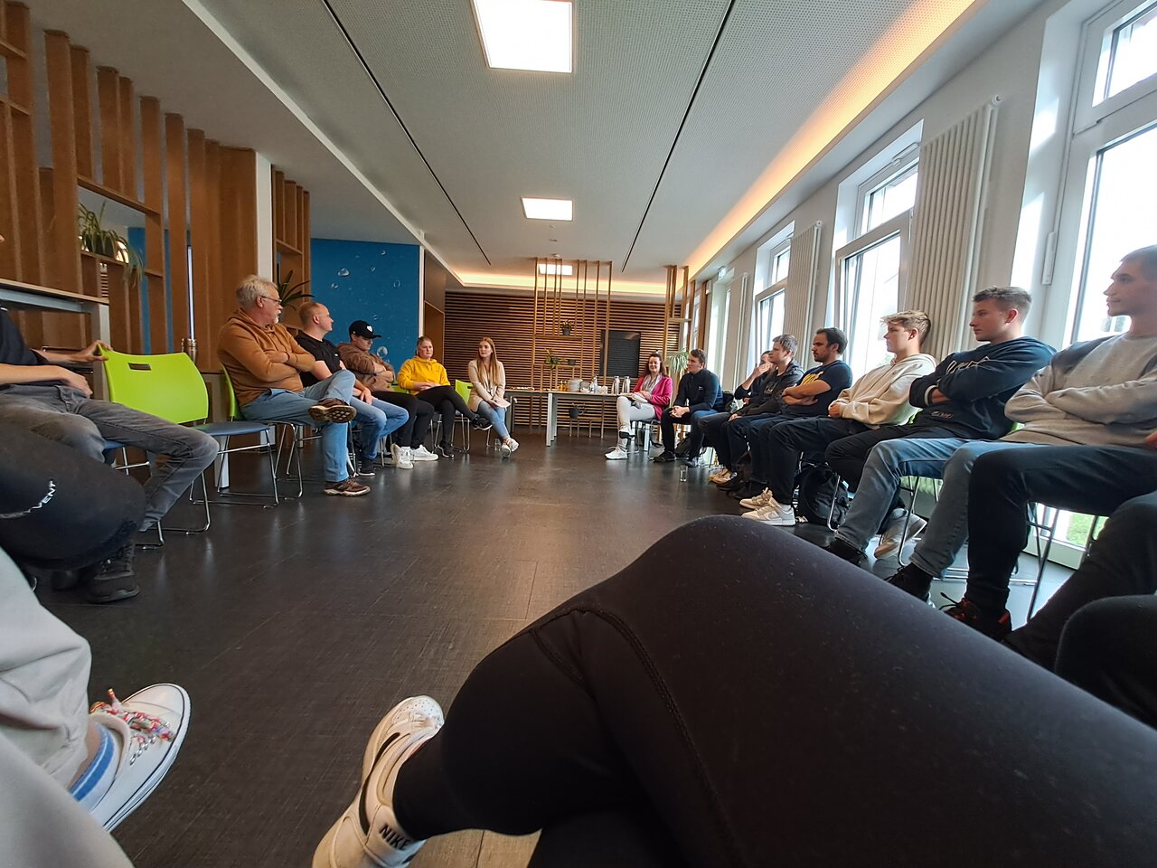 Viele Personen, die sich in einem Saal gegenübersitzen. 