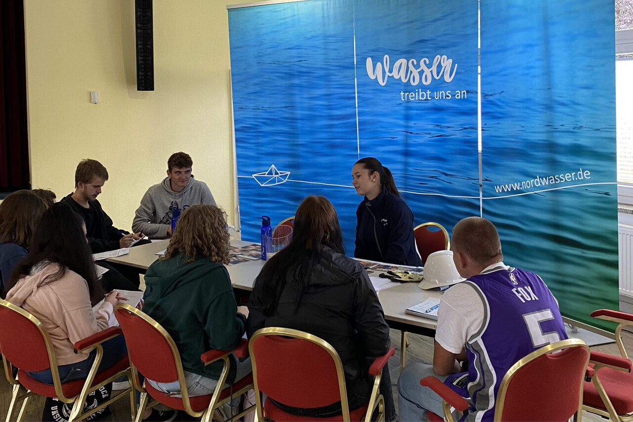 Personen, die um einen Tisch herum arbeiten.