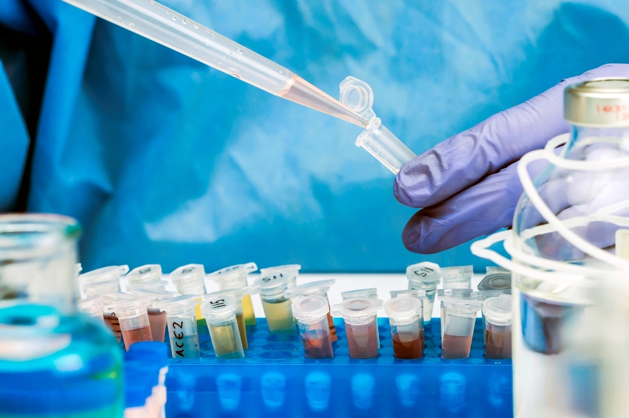 Hand pipettiert Flüssigkeit in Probenröhrchen im Labor