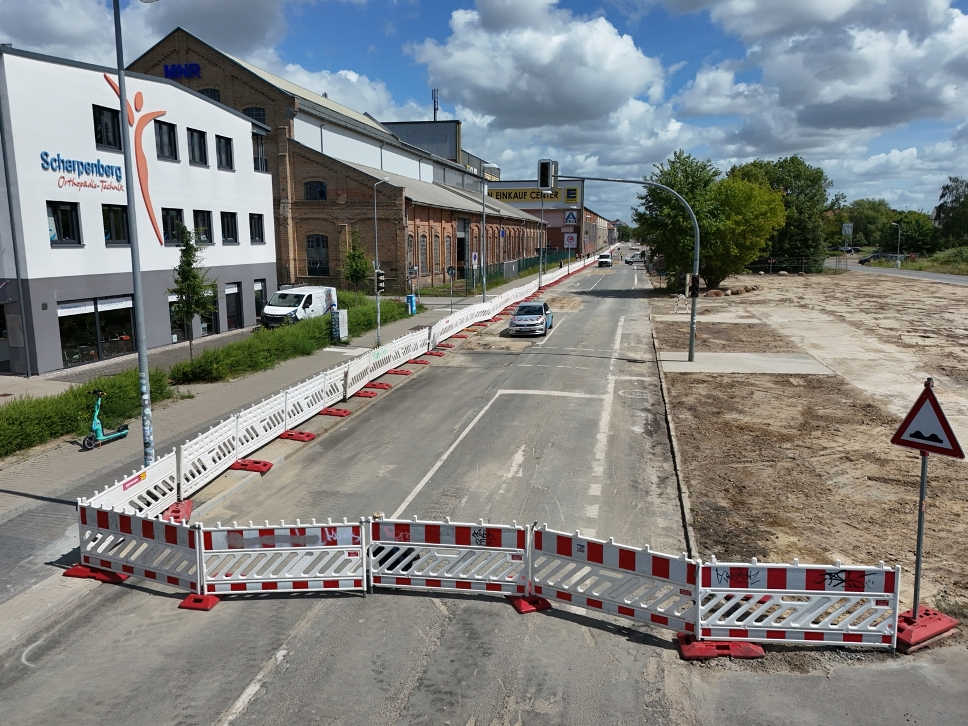 Blick auf eine zweispurige Straße, die durch einen Bauzaun umrandet ist.