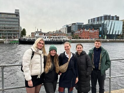 Foto einer Gruppe von fünf jungen Personene, die vor einem Fluss posieren. 
