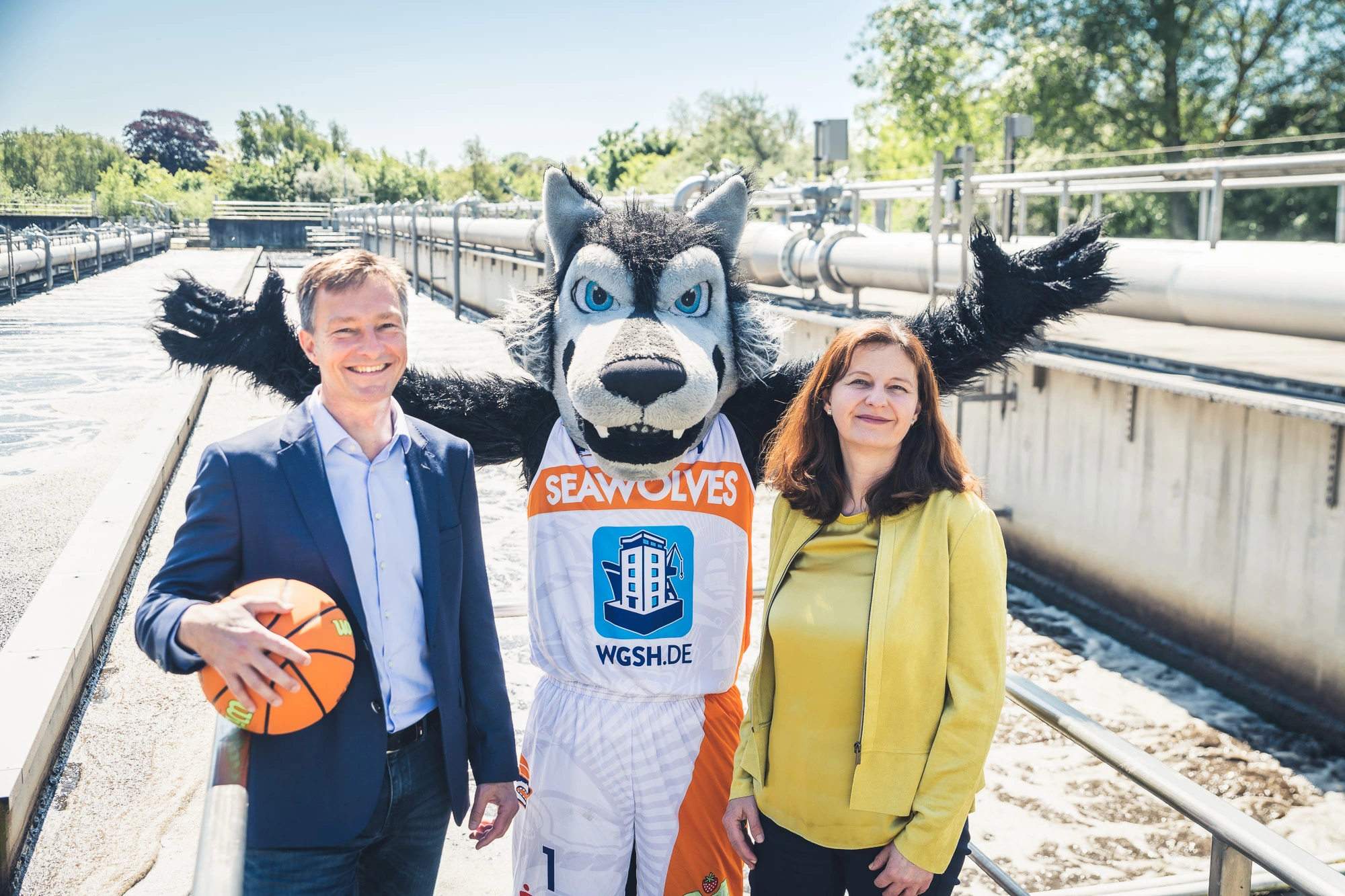 Herr Altmann und Frau Link mit Maskottchen Wolfi auf der Kläranlage